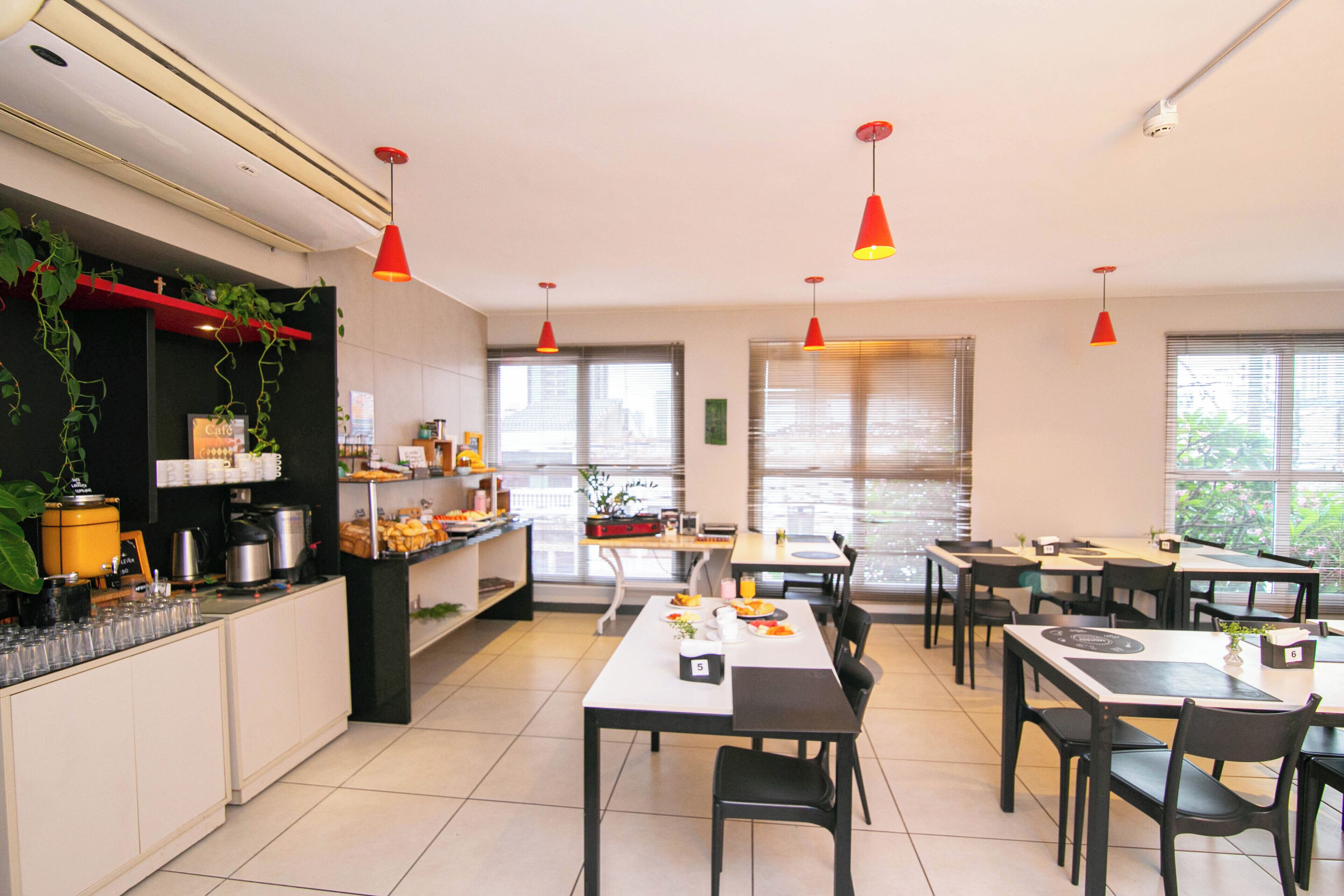 Un comedor moderno con mesas y sillas, una encimera de cocina con electrodomésticos y plantas colgantes.