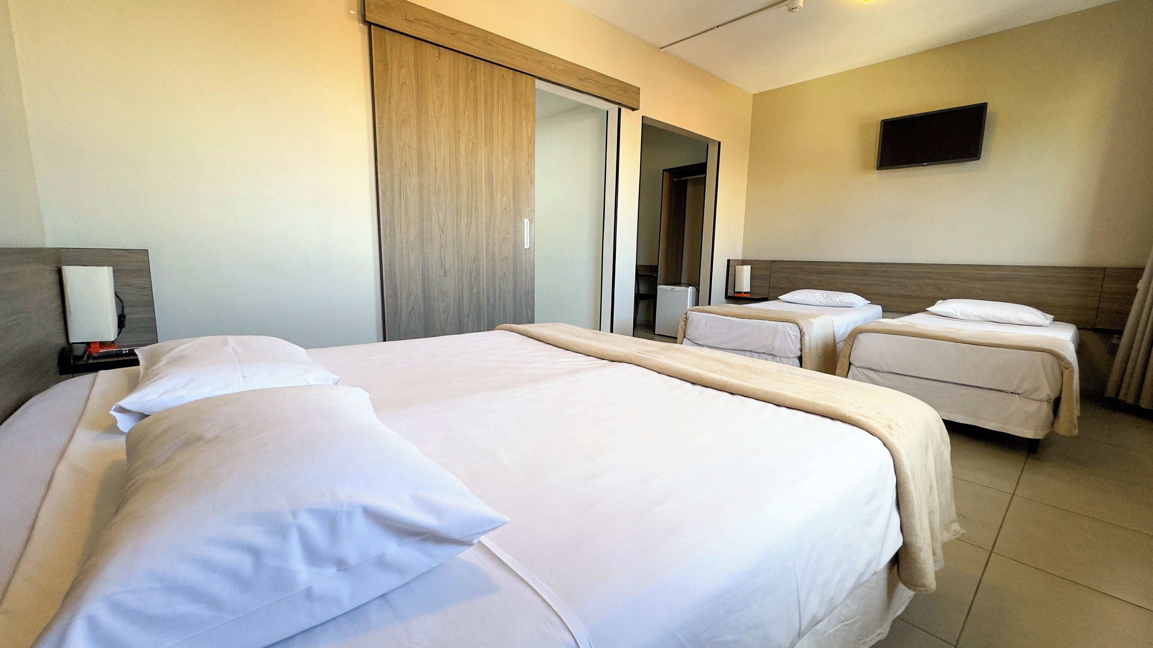 A hotel room with two beds, a flat-screen TV, and a mirror.