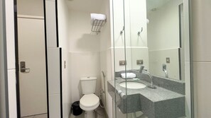 Een moderne badkamer met toilet, wastafel en een douchecabine van glas.