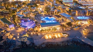 An aerial view of a resort with multiple swimming pools, beachfront areas, and well-lit buildings. - Nana Golden Beach - All Inclusive (Hersonissos)