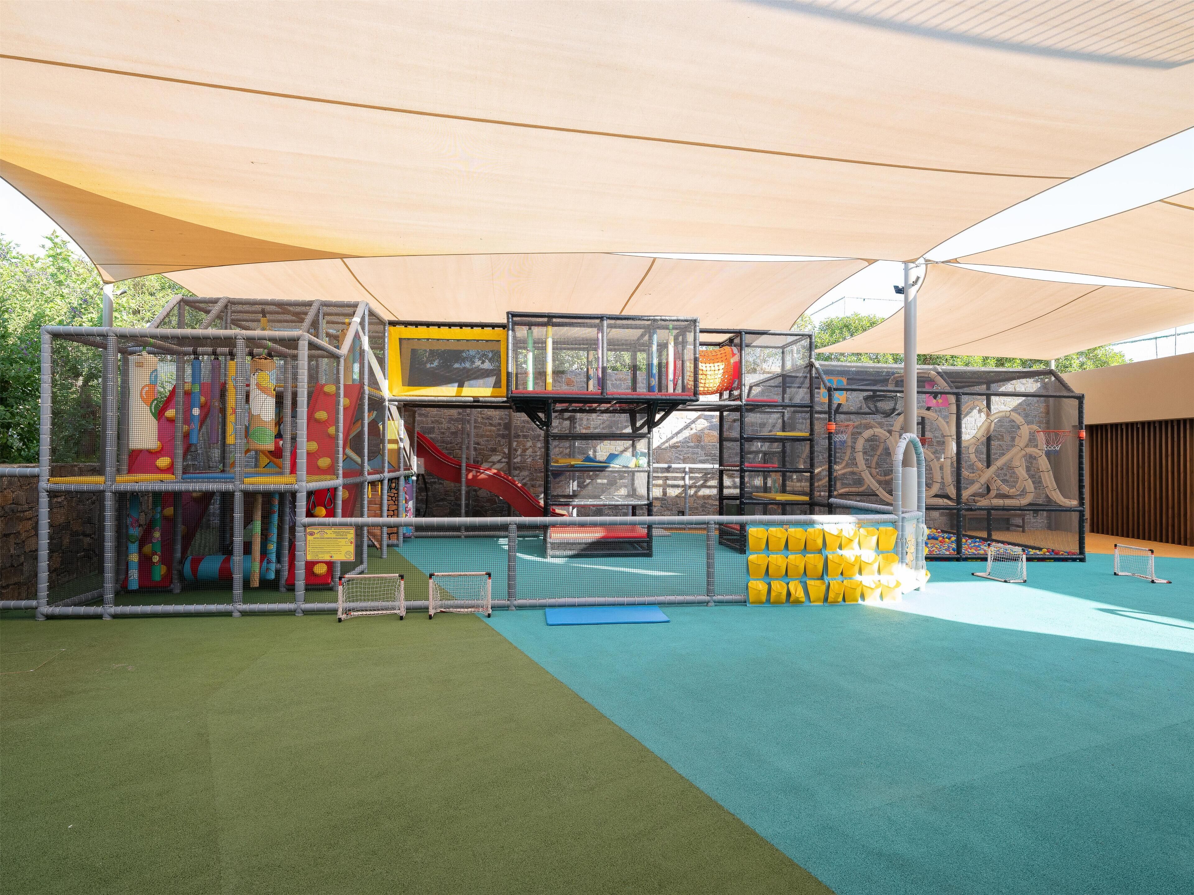 Uma área de recreação infantil com estruturas de escalada, escorregas e quadra de basquete.
