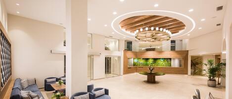 A spacious lobby with a central wooden ceiling feature, seating areas, and a reception desk.
