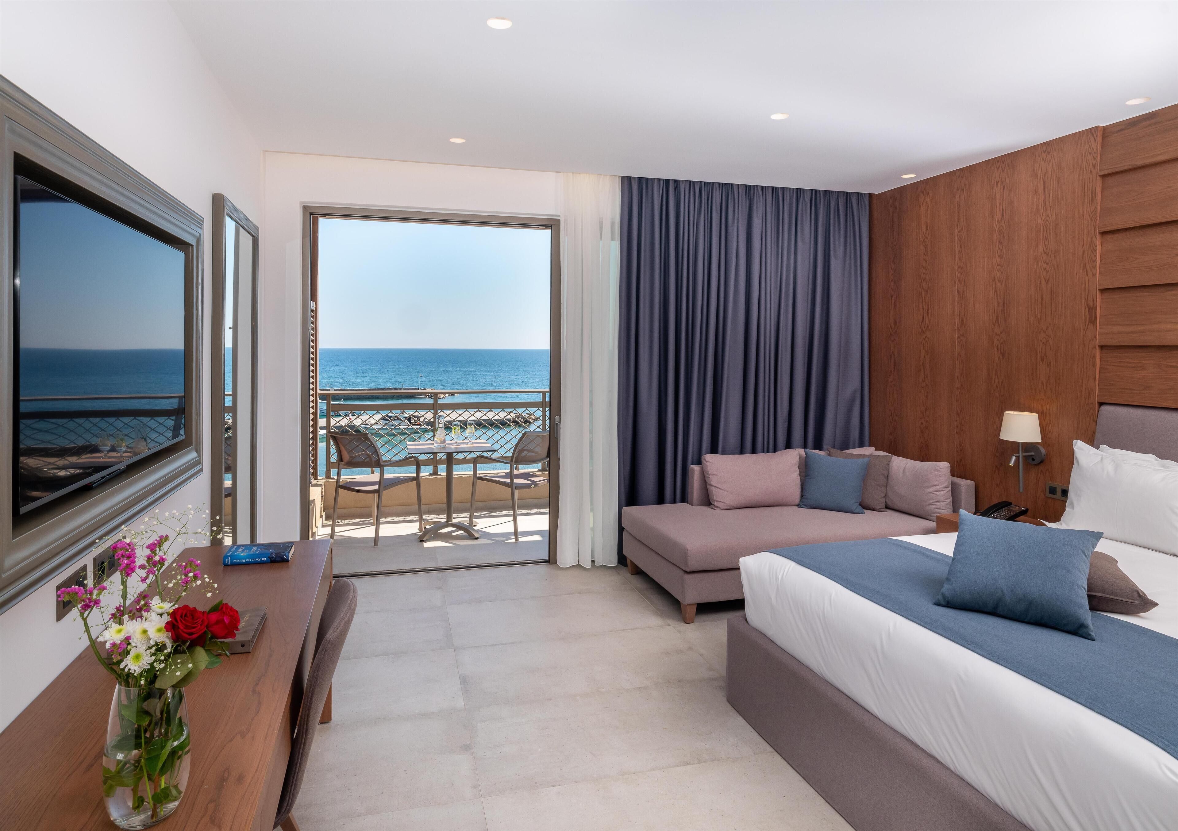 Ein Hotelzimmer mit Bett, Schreibtisch, Fernseher und Meerblick.