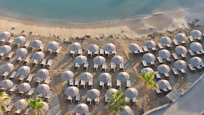 An aerial view of a beach with rows of sun loungers and umbrellas, a wooden walkway, and a palm tree. - Nana Golden Beach - All Inclusive (Hersonissos)