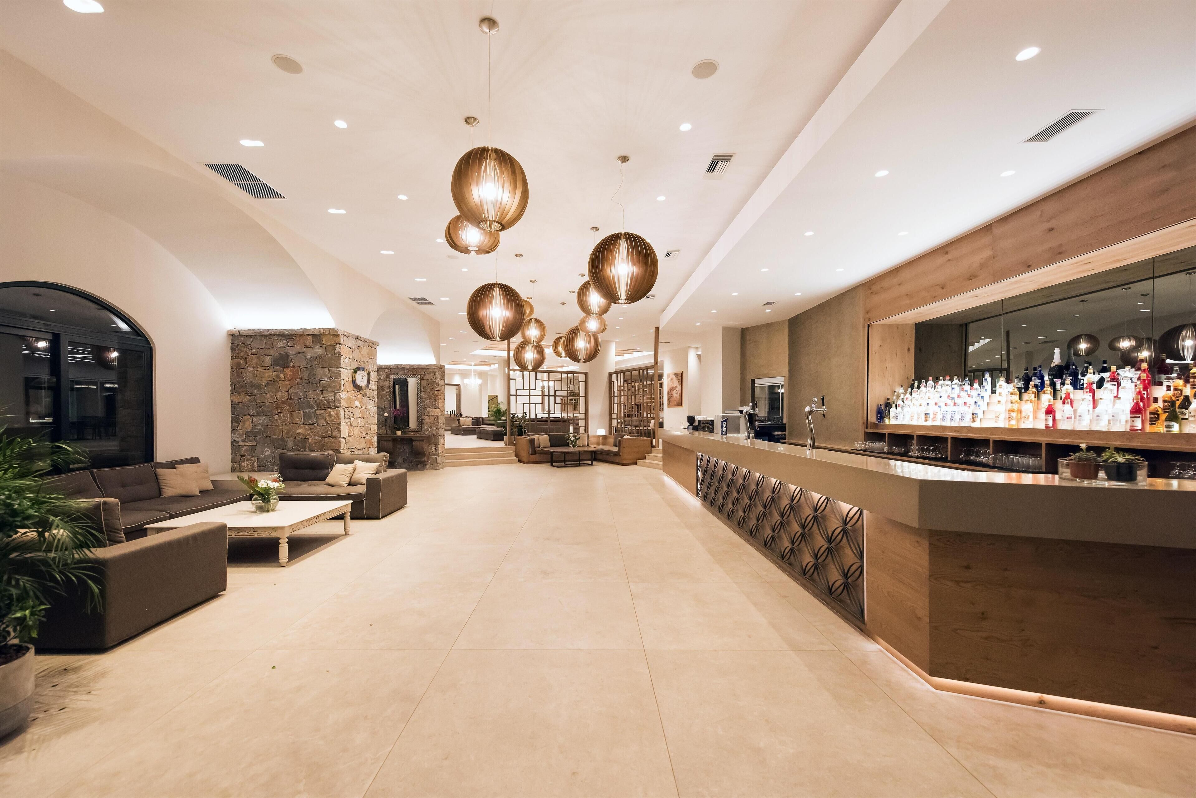 Een ruime lobby met een bar, zithoekjes en een wand van steen.
