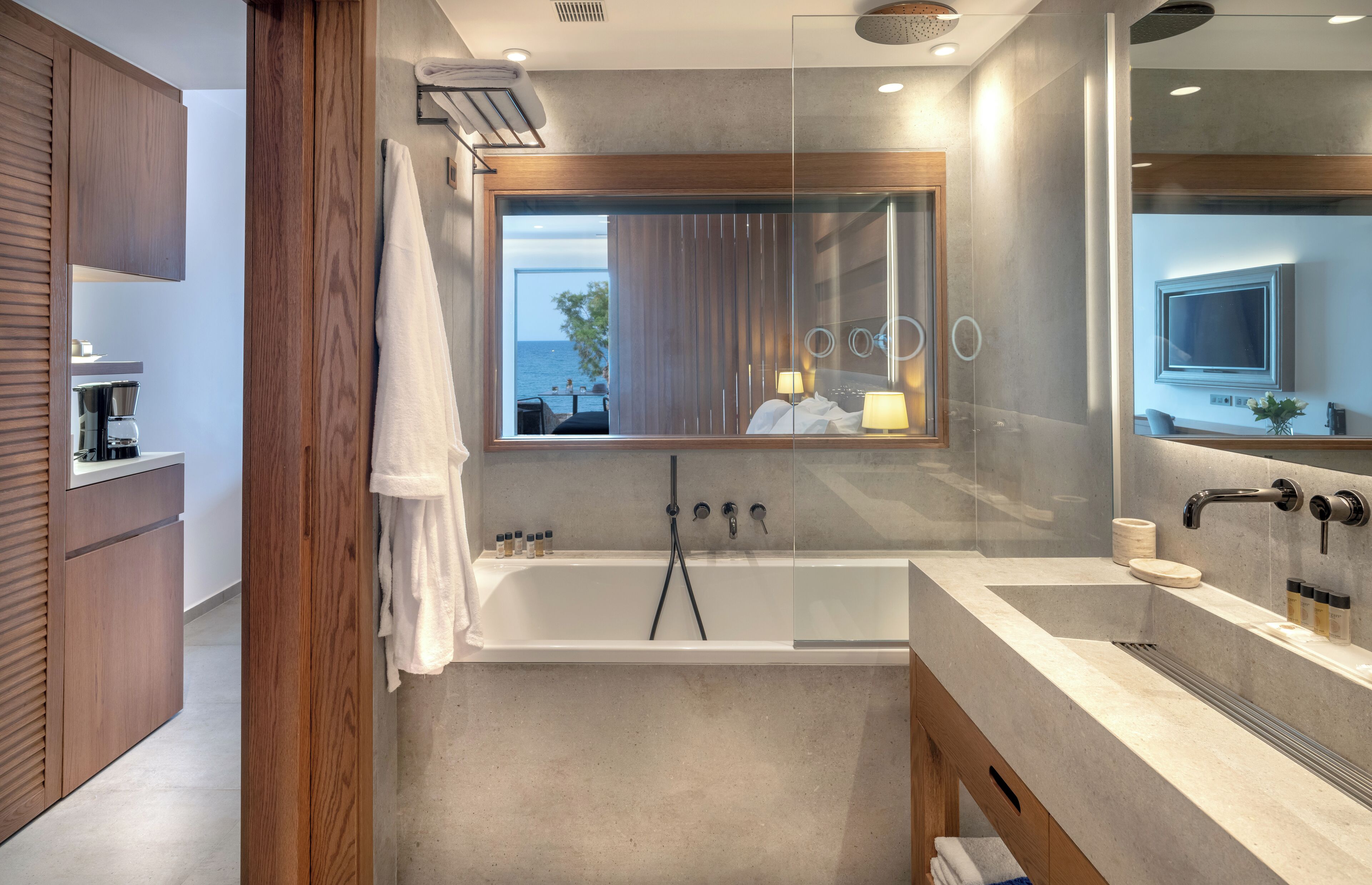 Une salle de bain moderne avec une baignoire, un grand miroir et une vue sur la mer.