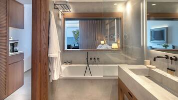 Un baño moderno con bañera, un espejo grande y vista al mar.