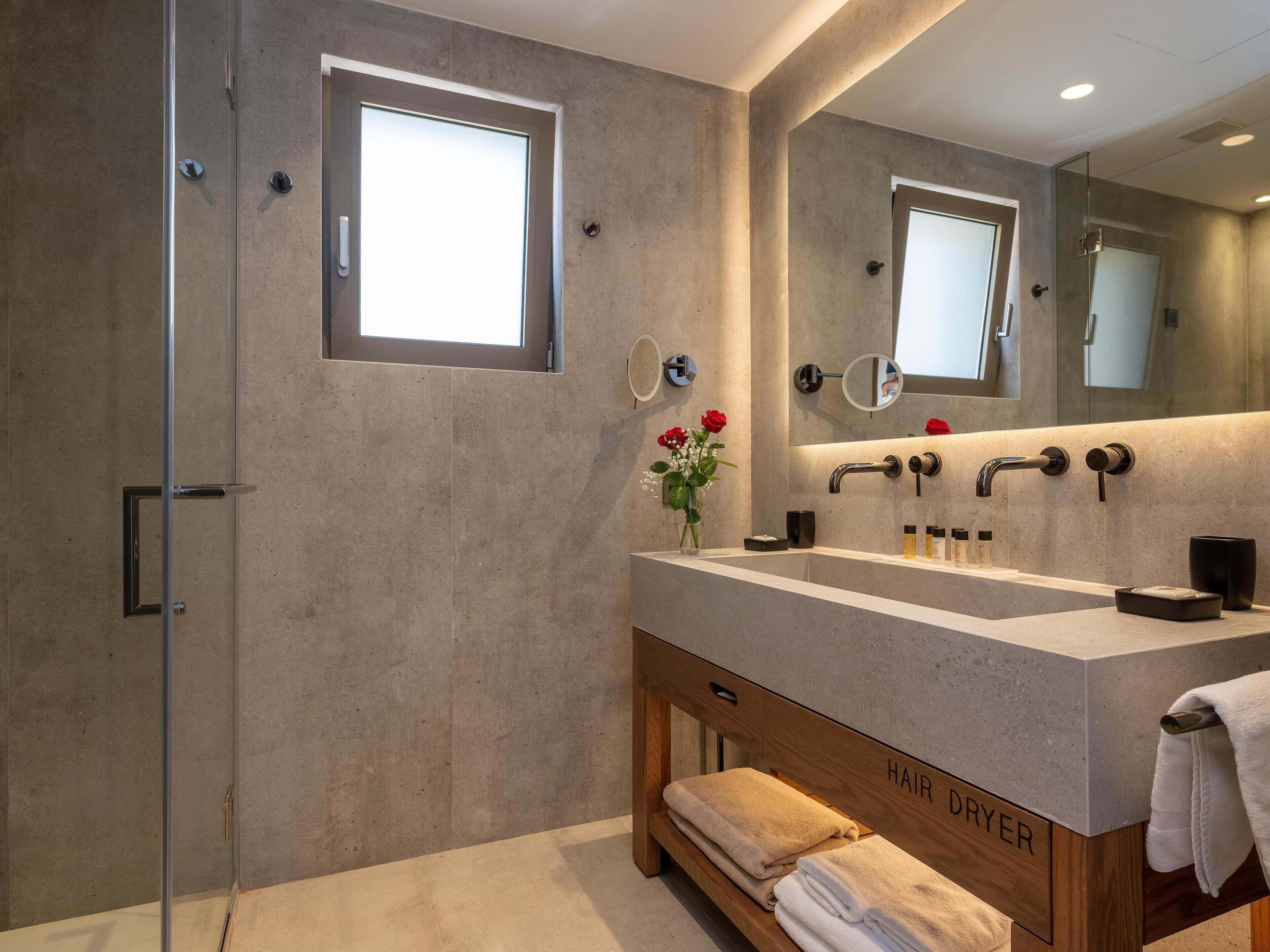 Casa de banho moderna com um espelho grande, duas lavatórios, secador de cabelo e cabine de duche em vidro.