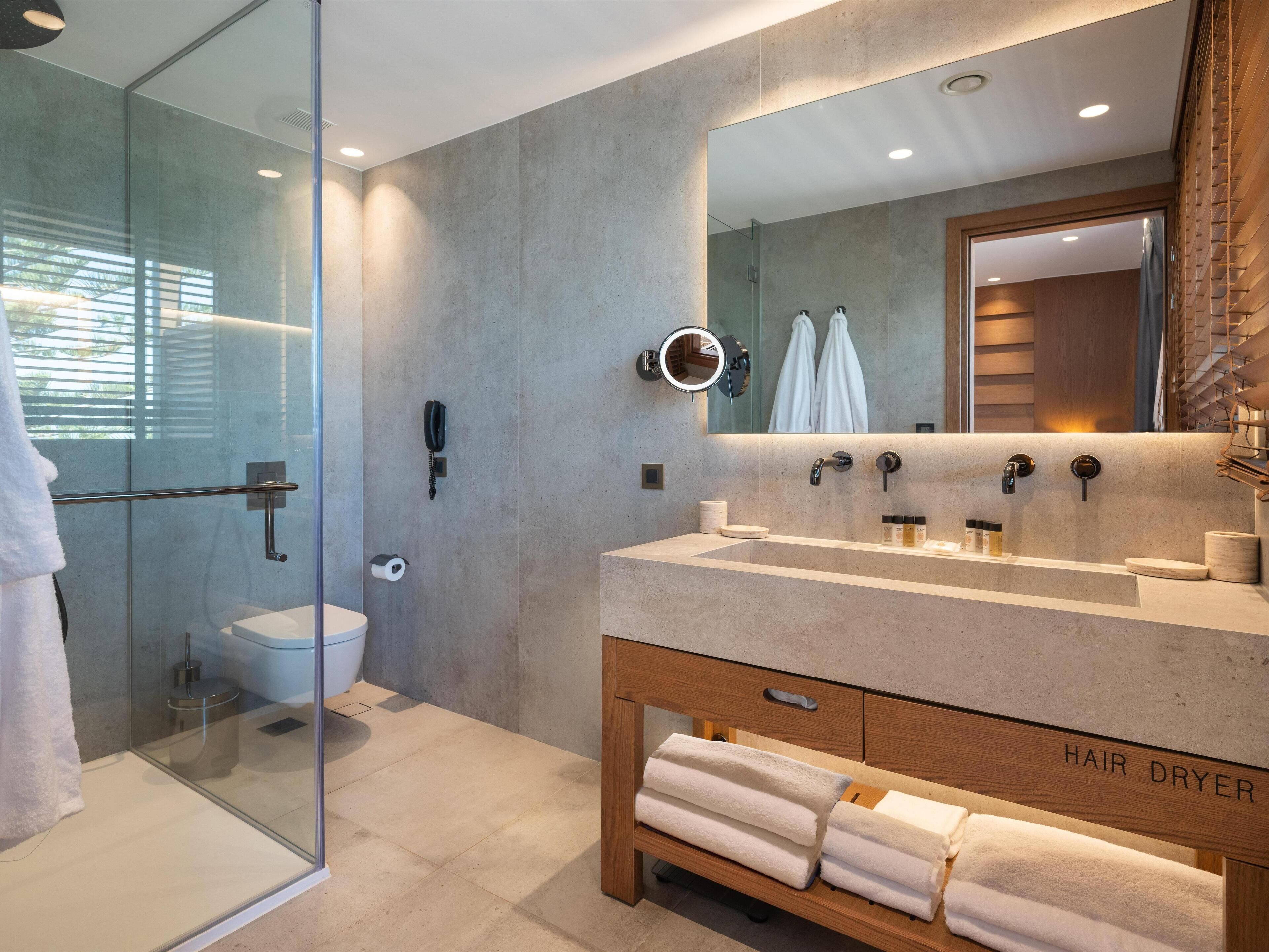 A modern bathroom with a glass shower enclosure, a vanity with a mirror, and a hair dryer shelf.