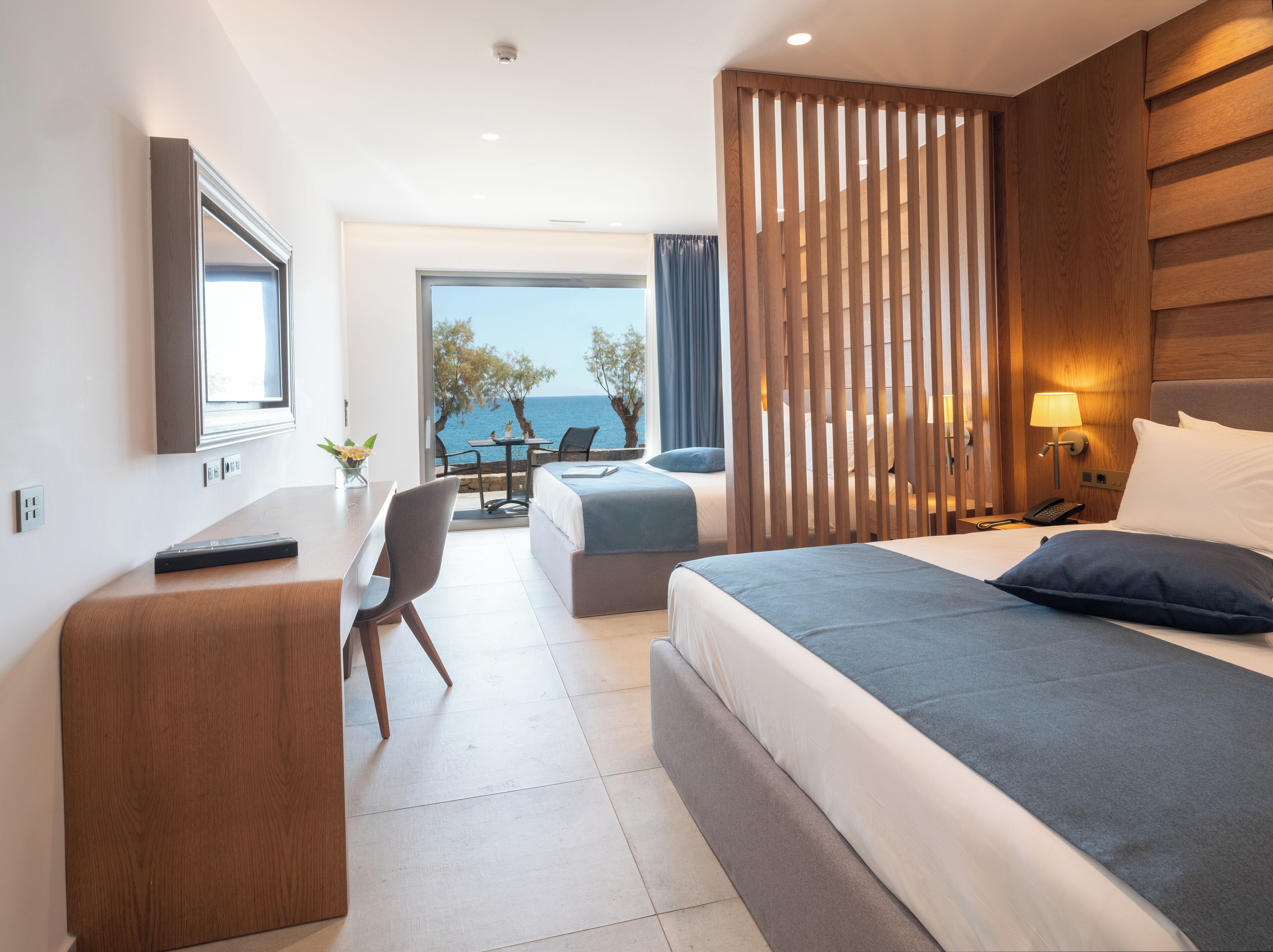Una habitación de hotel moderna con una cama grande, un escritorio, una silla y vista al mar.