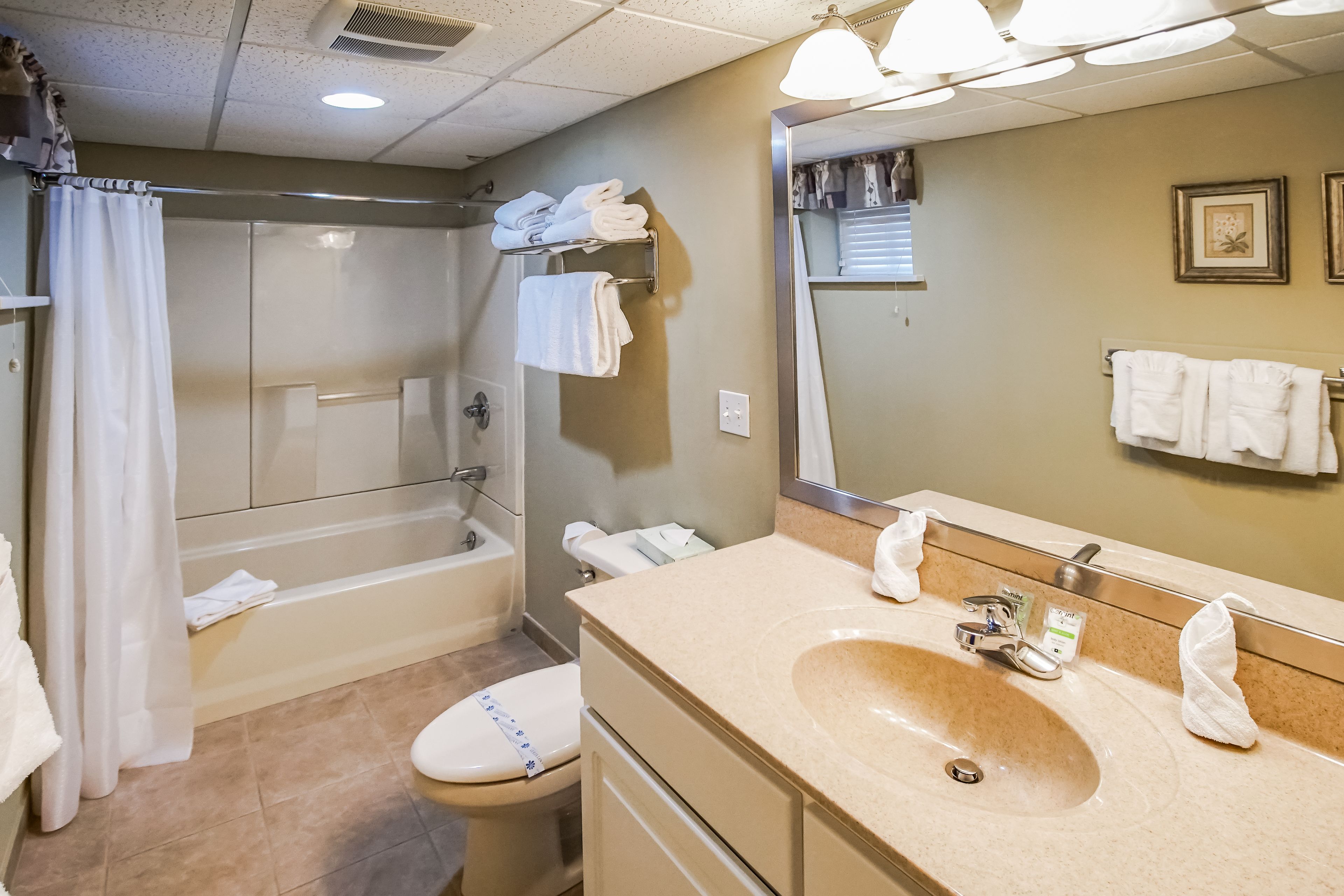 A bathroom with a bathtub, toilet, sink, and a large mirror.