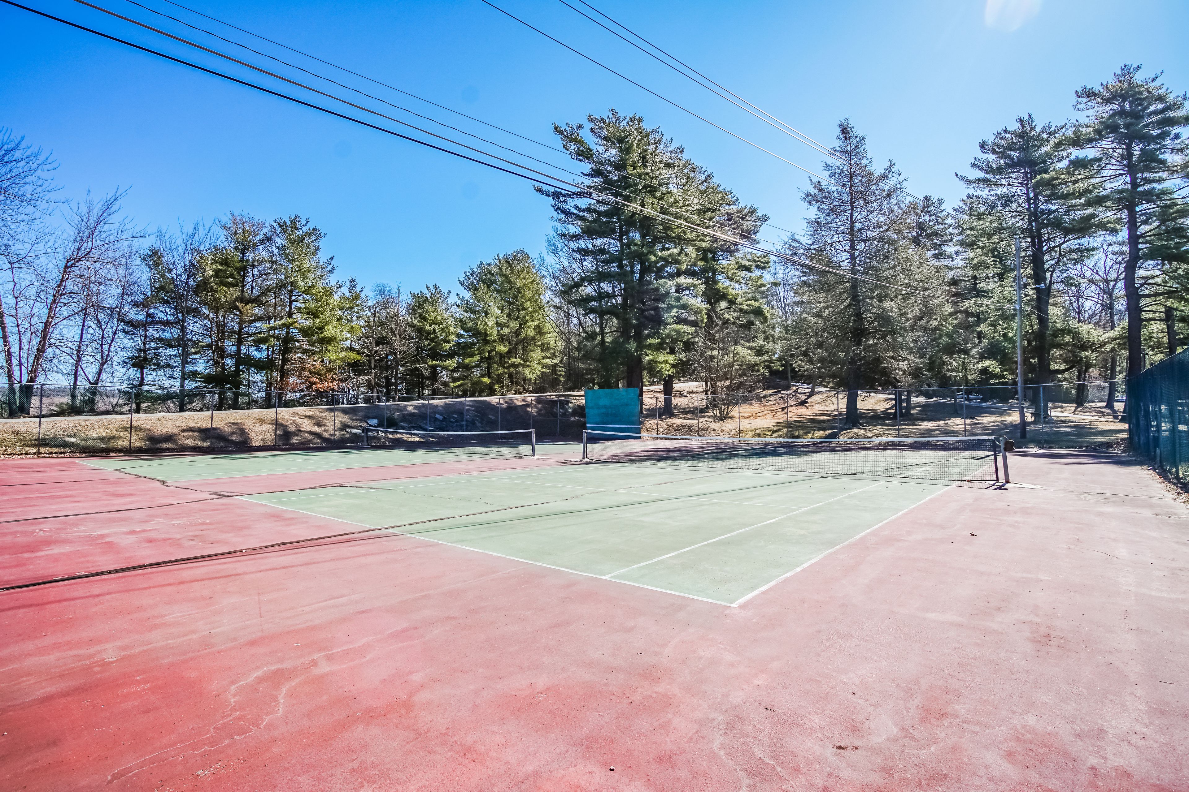 An outdoor tennis court surrounded by trees.