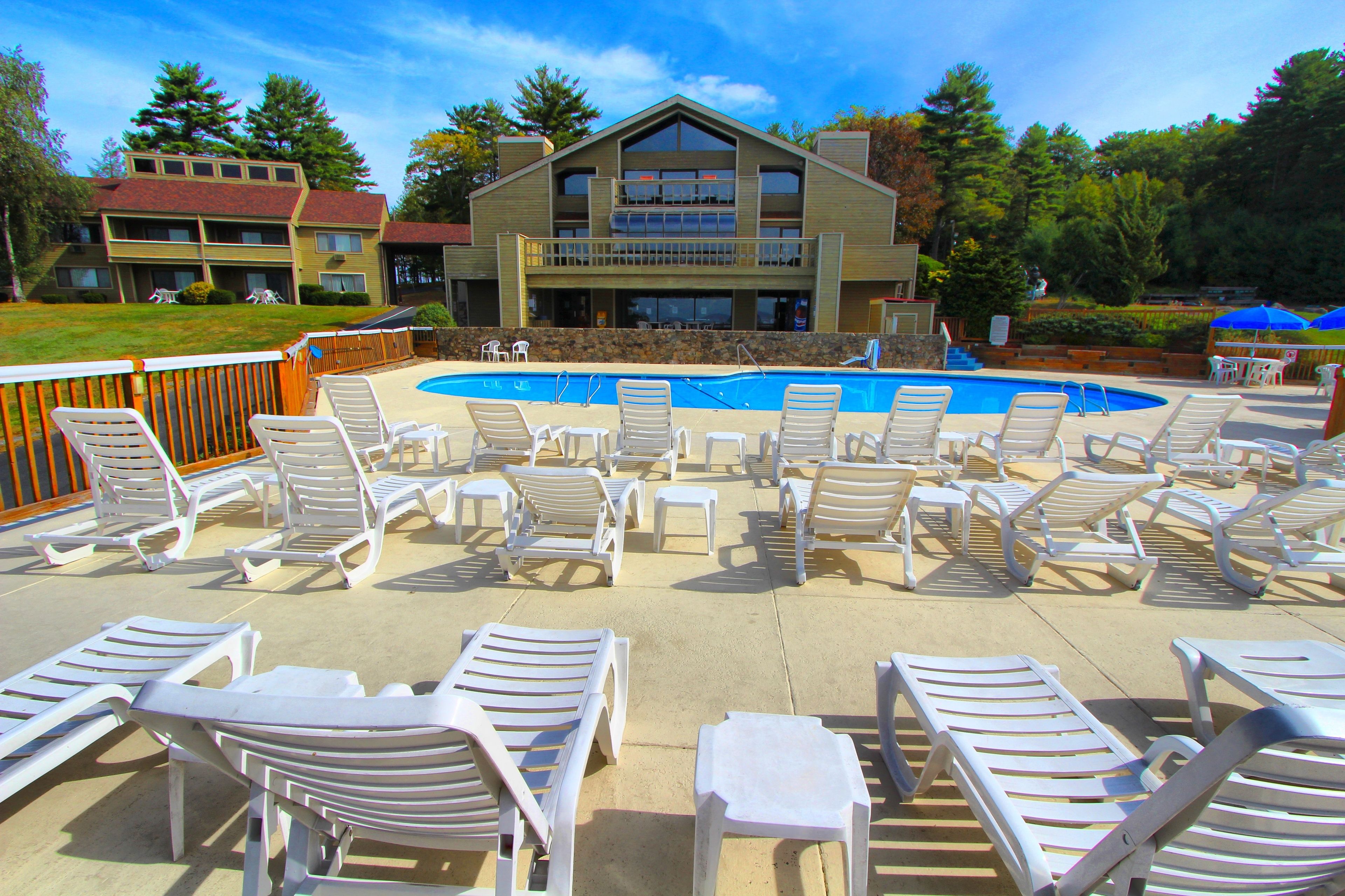 A pool area with multiple lounge chairs and a pool.