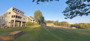 A modern building with multiple floors and large windows, surrounded by a well-maintained lawn and trees. - Tanglwood Resort (Hawley)