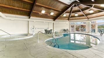 Une piscine intérieure avec un sol en pierre et des poutres en bois au plafond.