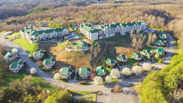 An aerial view of a resort with multiple buildings, a central pool, and a parking area. - Sunrise Ridge Resort by Coolvacay (Pigeon Forge)