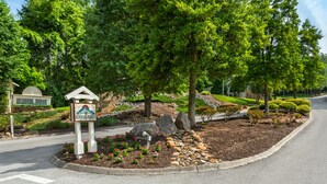 A landscaped area with a sign for Sunrise Ridge, featuring a well-maintained garden with rocks, shrubs, and a small water feature. - Sunrise Ridge Resort by Coolvacay (Pigeon Forge)