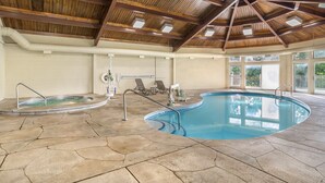 An indoor swimming pool with a stone floor, wooden ceiling beams, and a view of greenery outside. - Sunrise Ridge Resort by Coolvacay (Pigeon Forge)