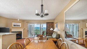 A spacious dining area with a wooden table and chairs, a chandelier, and a view of the outdoors through large windows. - Sunrise Ridge Resort by Coolvacay (Pigeon Forge)