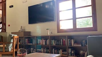 Una sala de estar acogedora con un televisor de pantalla plana montado en la pared, una mesa de centro de madera, un sofá cómodo y una estantería llena de libros.