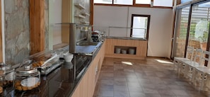 A modern kitchen with a glass-top counter, stainless steel appliances, and a stone wall. - Elea Terra Hotel (Faistos)