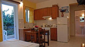 A compact kitchen with wooden cabinets, a refrigerator, and a dining area with a table and chairs.