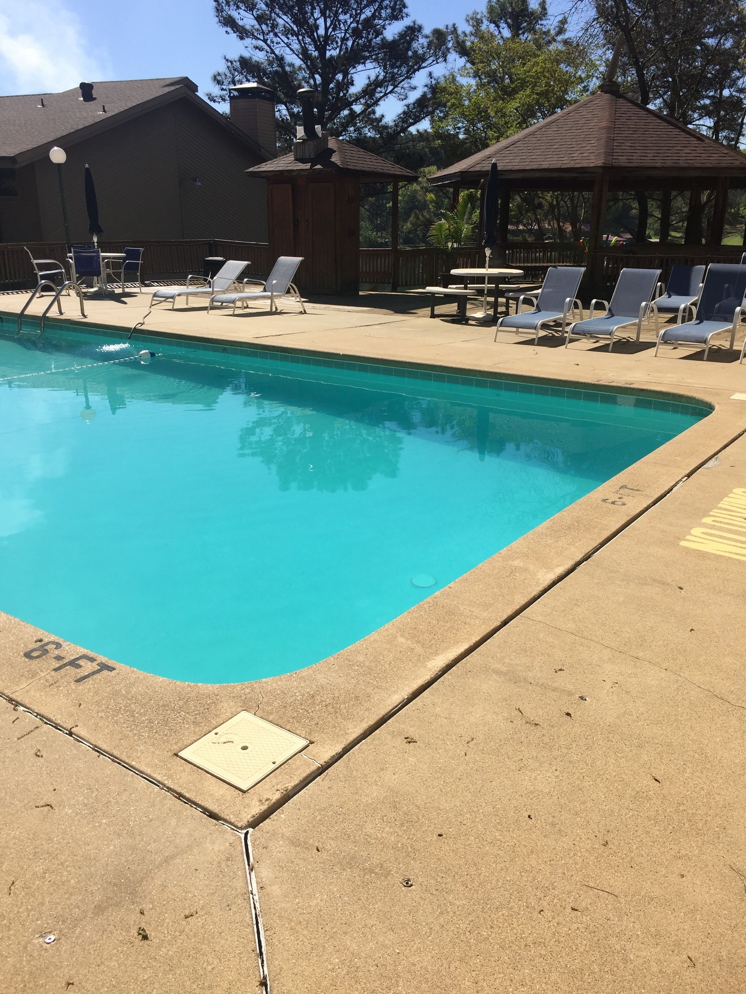 Una piscina con sillas de descanso y un pabellón.