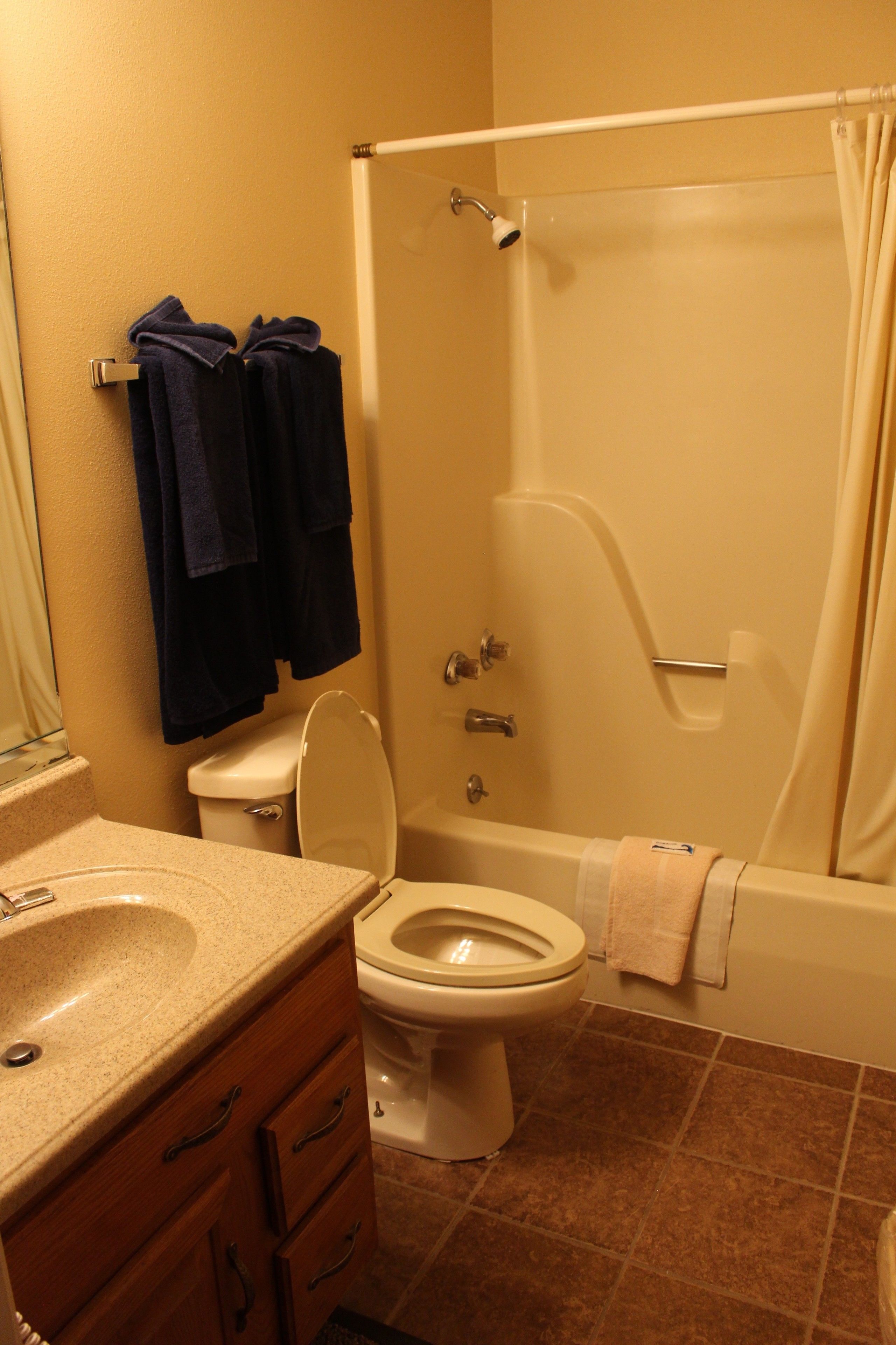 A bathroom with a toilet, sink, and bathtub. There are towels hanging on the wall and a shower curtain.