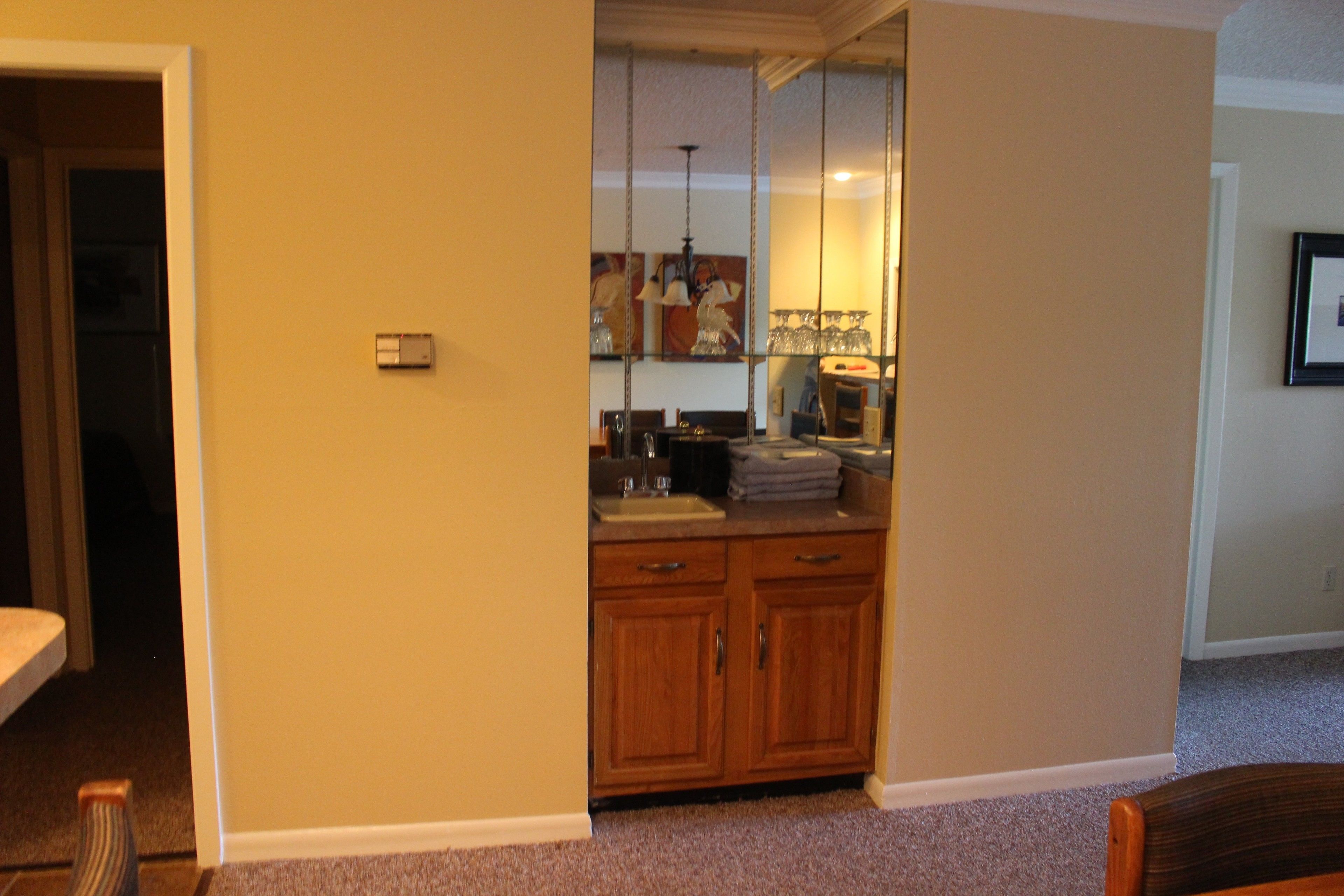 A room with wooden cabinets, a sink, and a mirror.