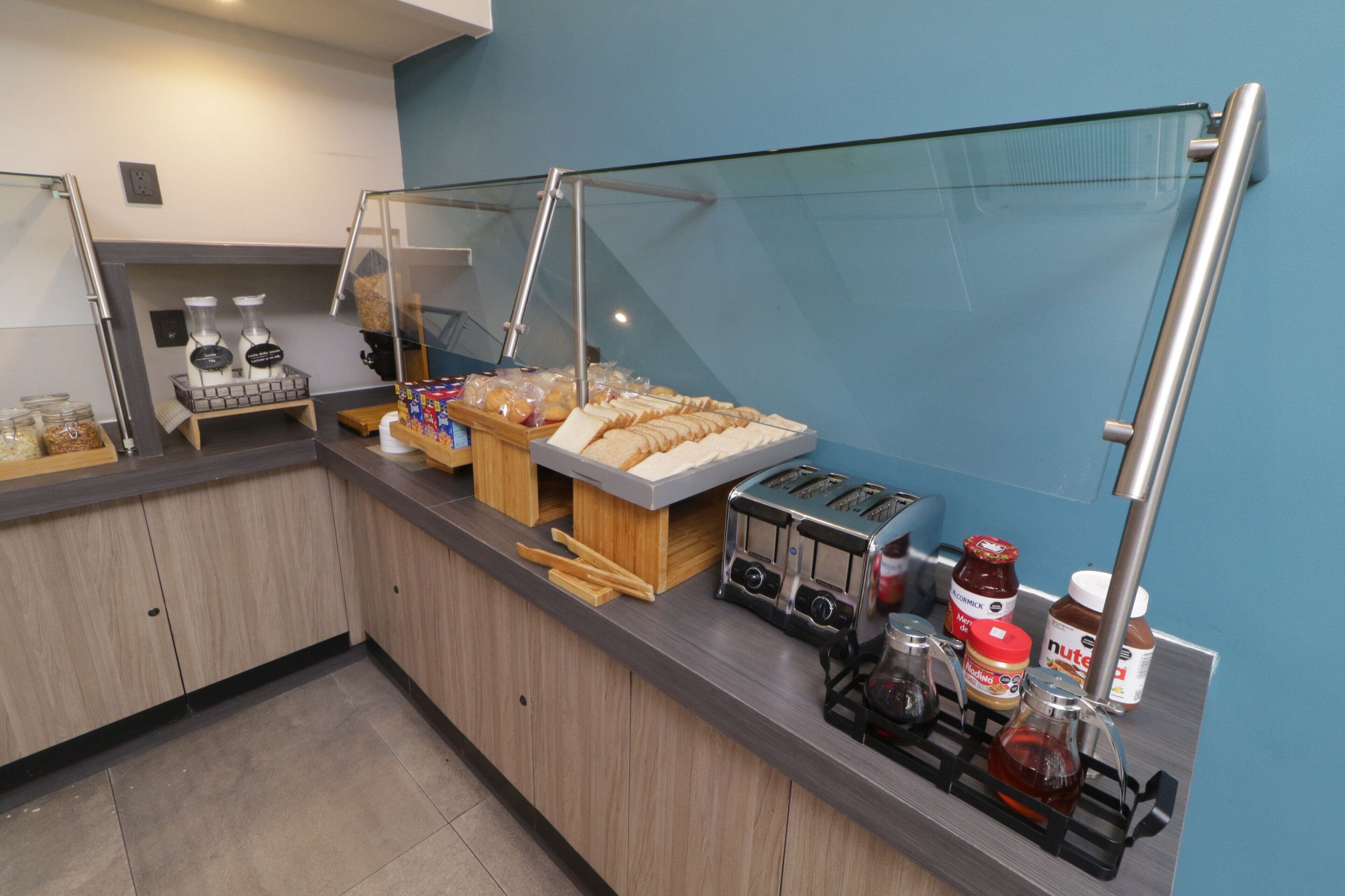 A breakfast bar with various food items, a toaster, and condiments.