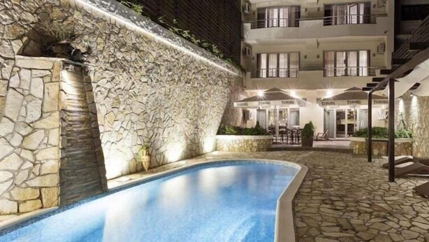 A swimming pool with stone walls and a covered seating area with lounge chairs. - Belgrade Boutique House (Belgrade)