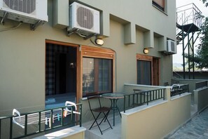 Zona salotto all'aperto con tavolo e sedie, condizionatori e una finestra con vista.