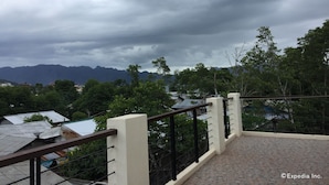 A balcony with a metal railing overlooking a mountainous landscape and a cloudy sky. - Coron Visitors Hotel (Coron)