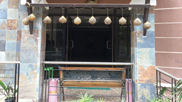 A hotel entrance with a wooden bench, a metal railing, and hanging decorative lights. - Coron Visitors Hotel (Coron)