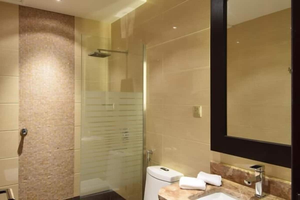 Une salle de bain moderne avec une douche à parois de verre, un grand miroir et un plan de toilette en marbre.