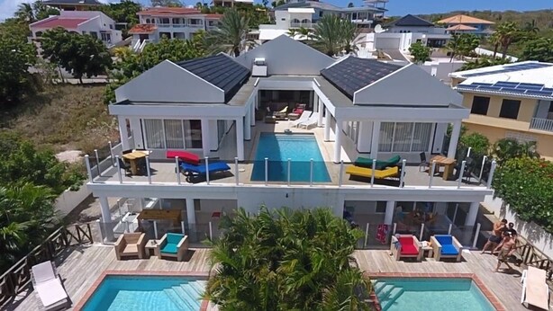 A resort with a central pool, multiple lounge areas, and a view of surrounding houses. - Sun Sea Sleep B&B (Willemstad)
