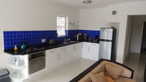 A modern kitchen with white cabinets, a black countertop, and blue tiles. - Sun Sea Sleep Apartments (Willemstad)