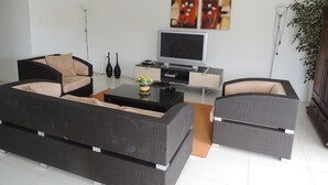 A modern living room with two black sofas, a coffee table, a flat-screen TV, and two paintings on the wall. - Sun Sea Sleep Apartments (Willemstad)