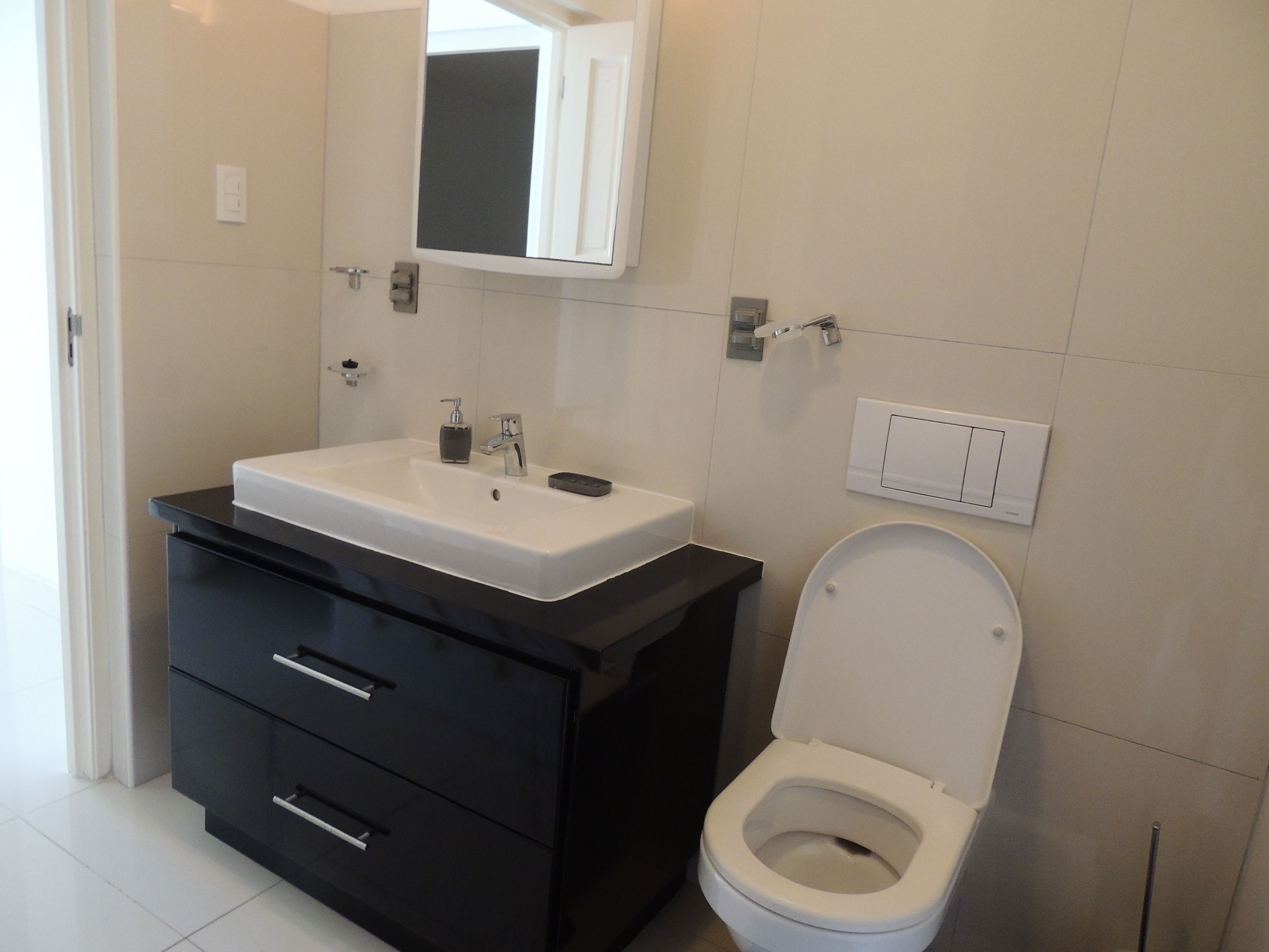 Ein modernes Badezimmer mit einem weißen Waschbecken, einer schwarzen Waschtischunterschrank und einer Toilette.