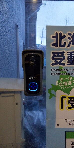 Un dispositivo de seguridad con luz azul, un letrero con texto en japonés y una bolsa de plástico colgada de un gancho.