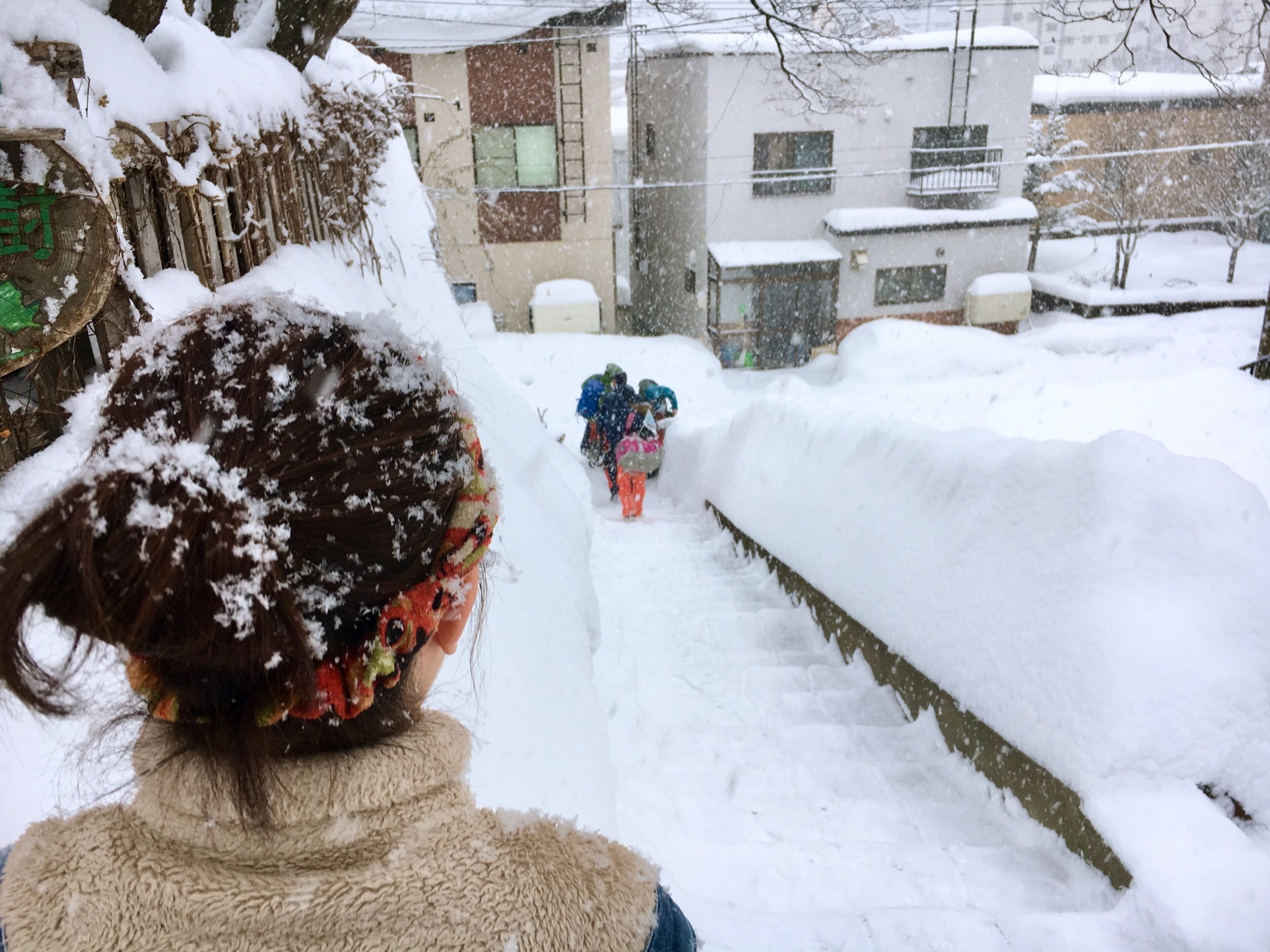 A snowy outdoor scene with a person walking down a snow-covered path.