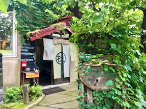 A traditional Japanese building with a wooden exterior, a red roof, and a sign with Japanese characters.