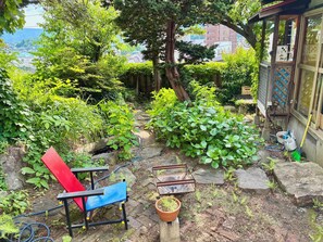 Ein Garten mit einem roten und blauen Stuhl, einem kleinen Tisch und einem Blumentopf.