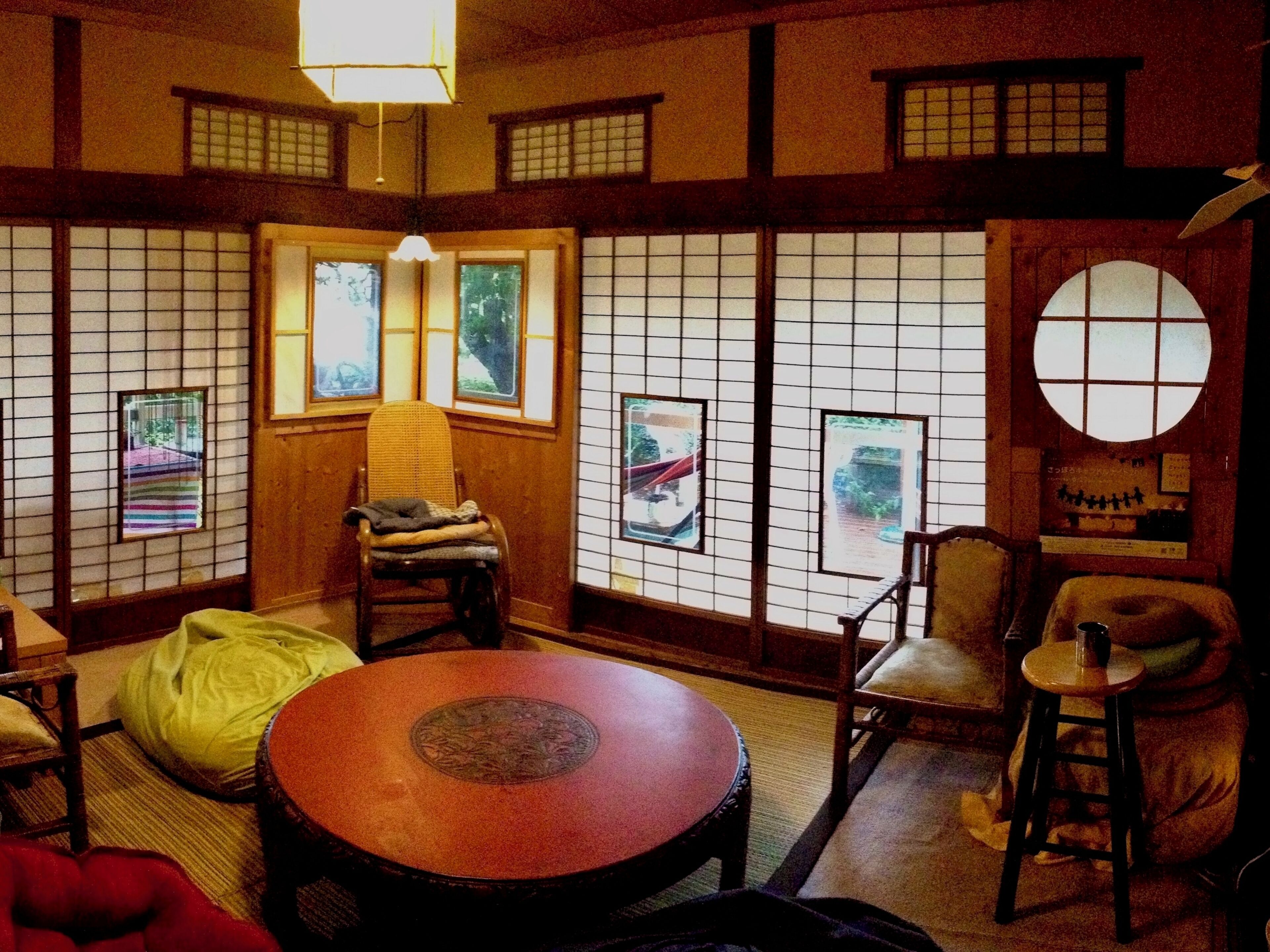Una habitación japonesa tradicional con suelo de tatami, una mesa redonda y puertas correderas shoji.