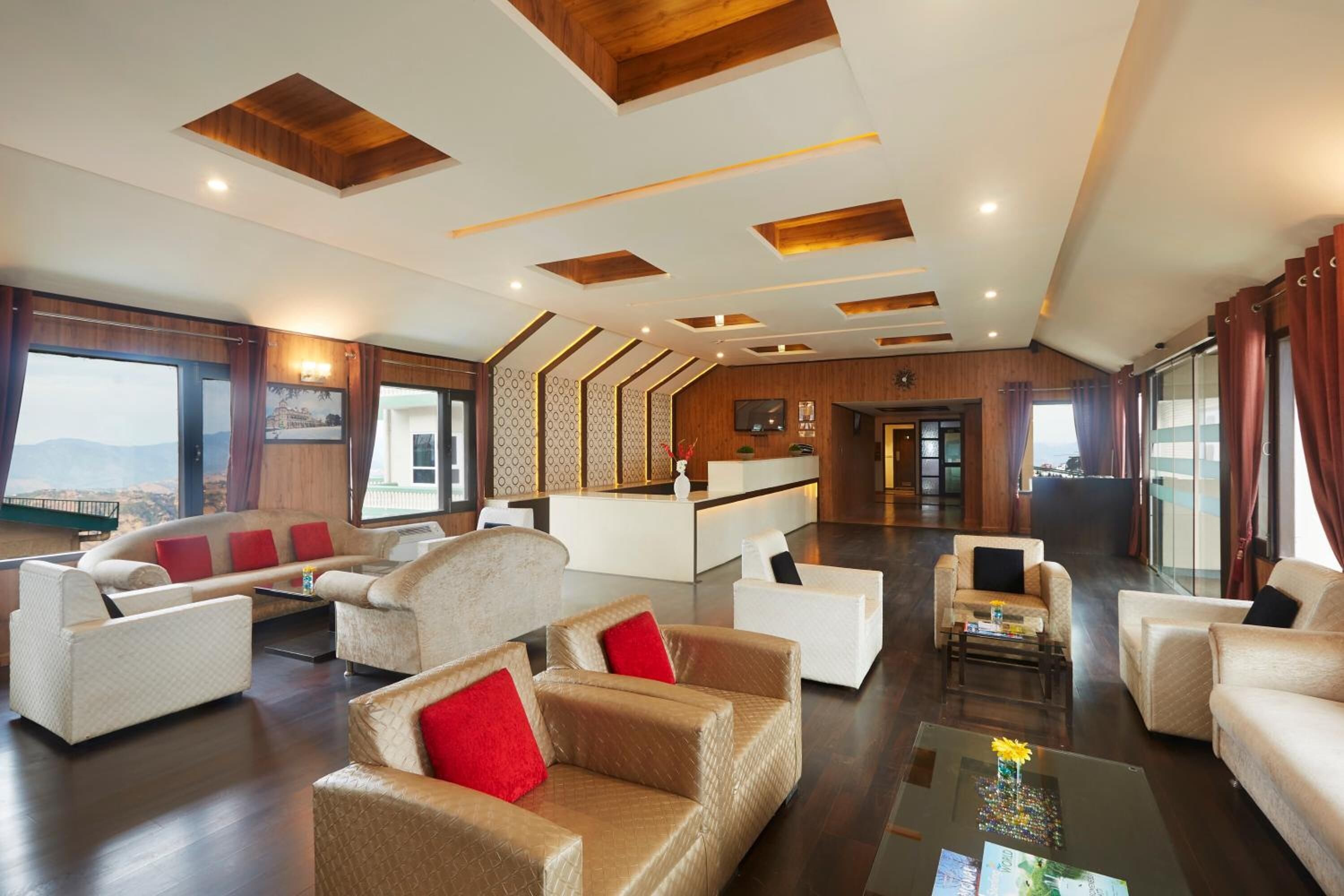 A spacious hotel lobby with multiple seating areas, a reception desk, and large windows offering a view.
