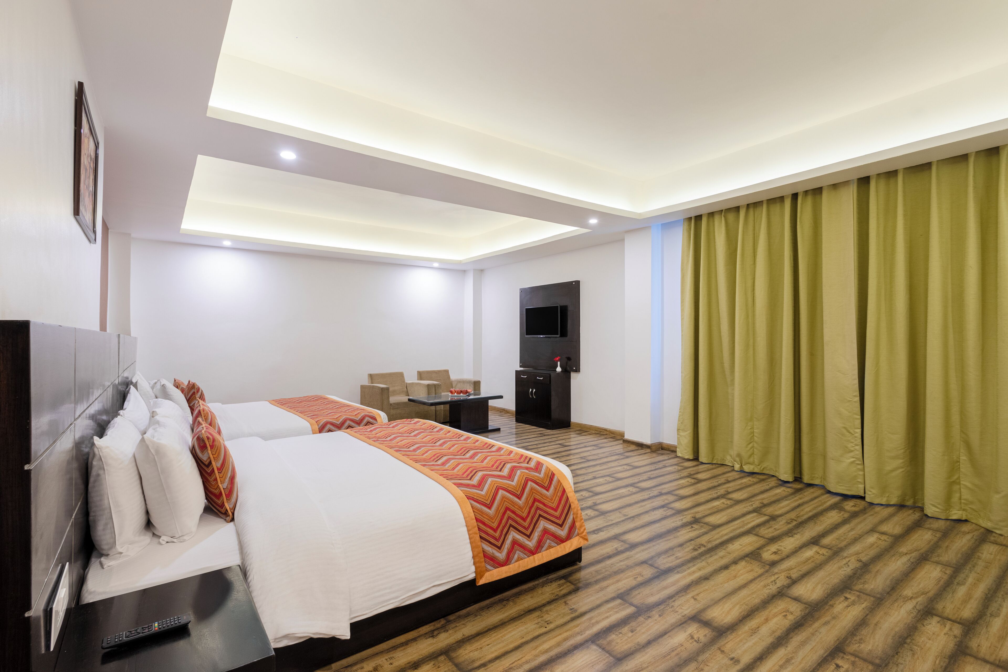 A hotel room with a bed, a desk, a TV, and a large window with curtains.