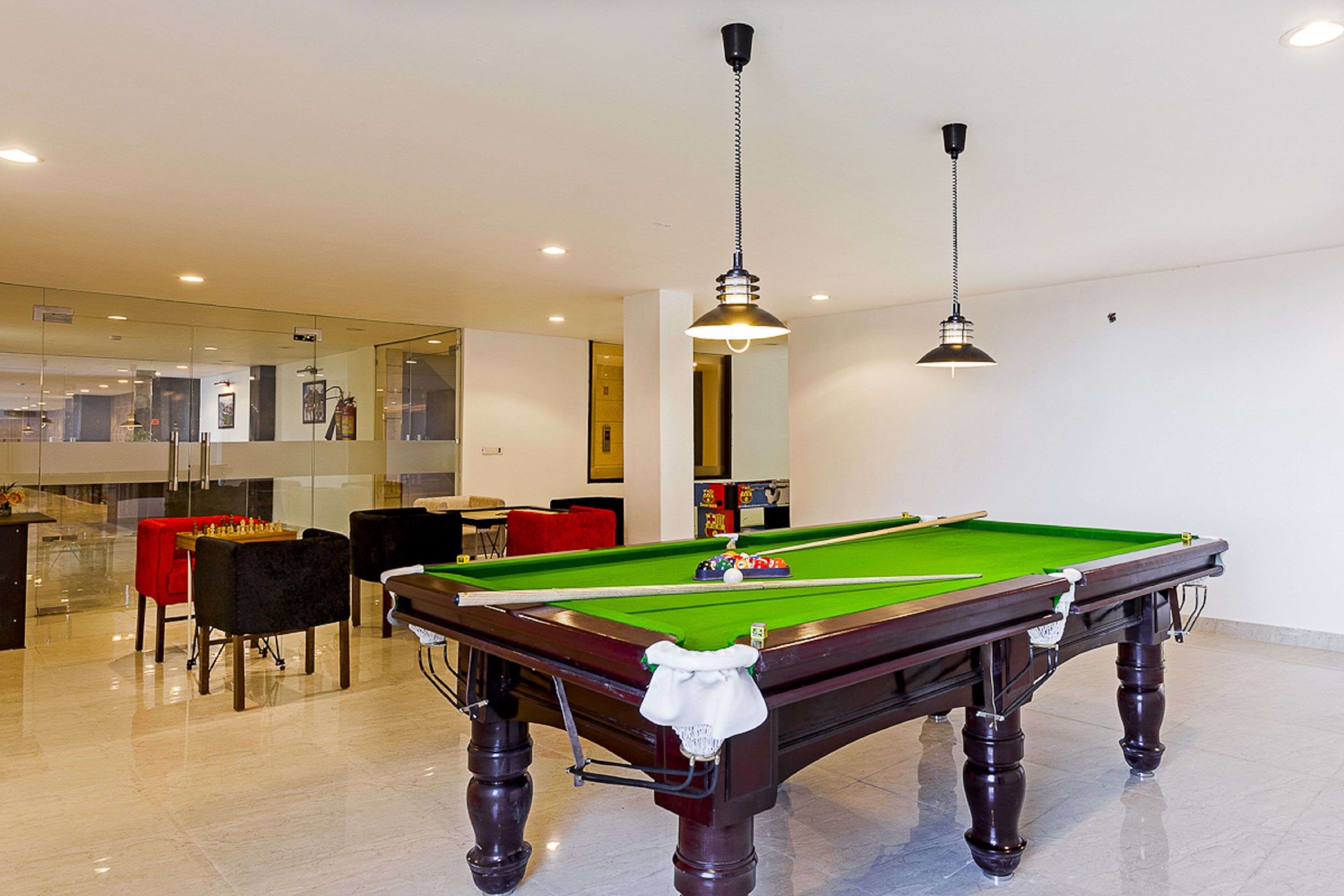 A pool table in a well-lit room with a modern design, including a bar area and seating.