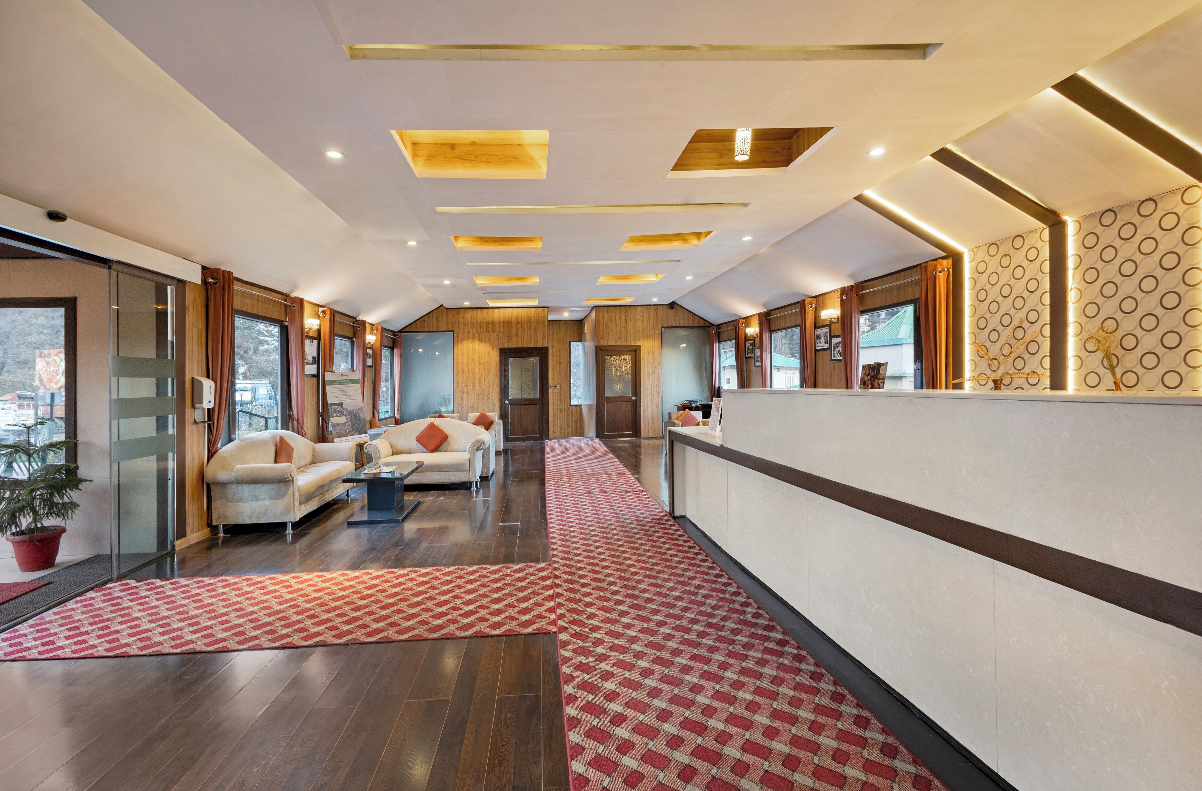 A hotel lobby with a reception desk, sofas, and a patterned rug.