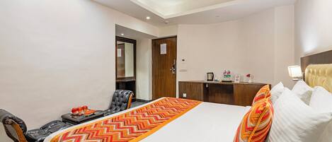 A hotel room with a bed, a desk, a chair, and a wardrobe.