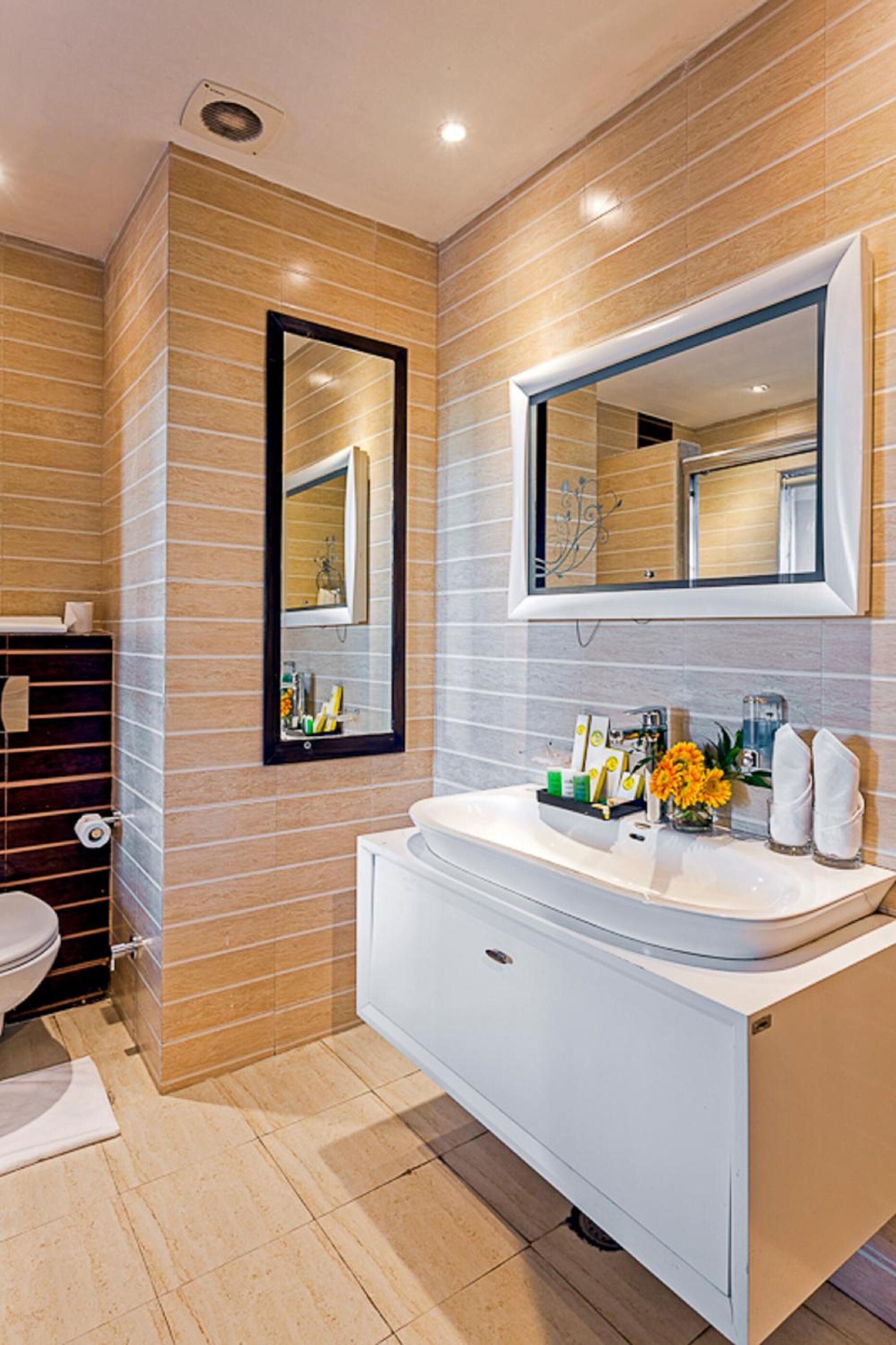 A modern bathroom with a white vanity, a large mirror, and a toilet.